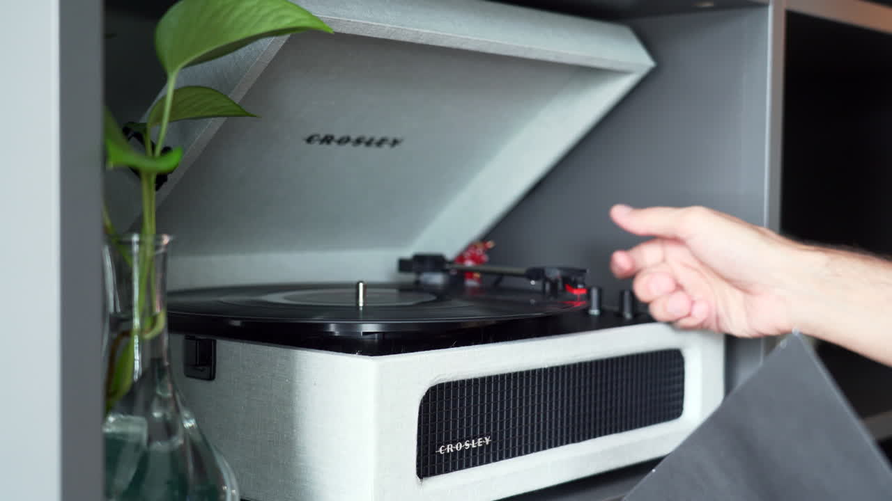 Man using an old record player: hands are taking out vinyl from its cover, place it on the record player and move the head to the vinyl to start the music.