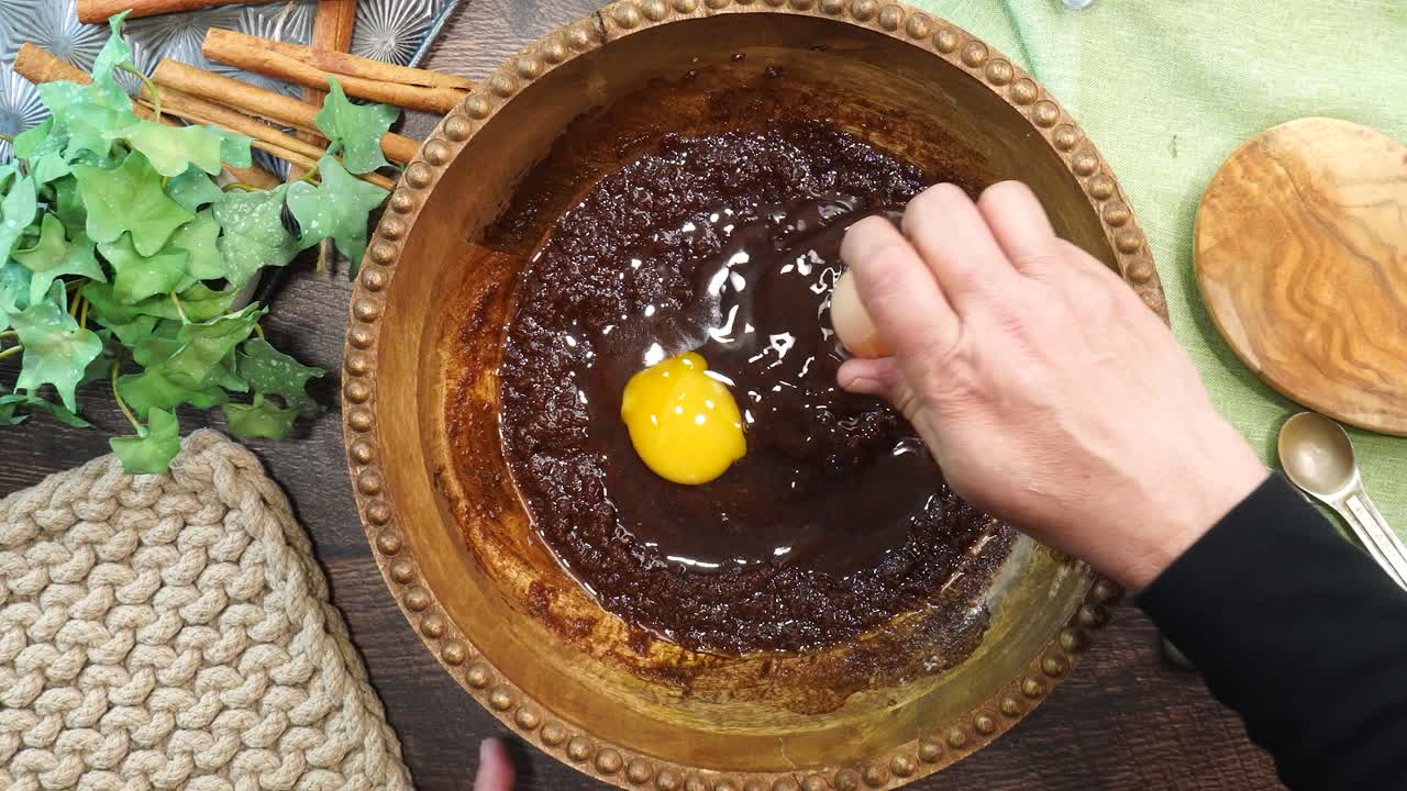 Baking a carrot cake loaf with cream cheese icing and topped with roasted salted pecans. Making a Autumn dessert with carrots, flour, sugar, nuts and frosting. Cracking eggs into the batter.