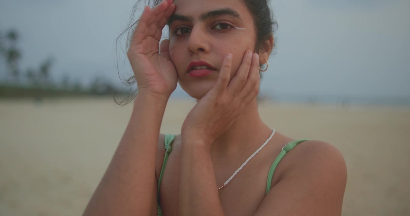 Ritratto di bellezza ravvicinato di giovane donna in posa sulla spiaggia con luce soffusa