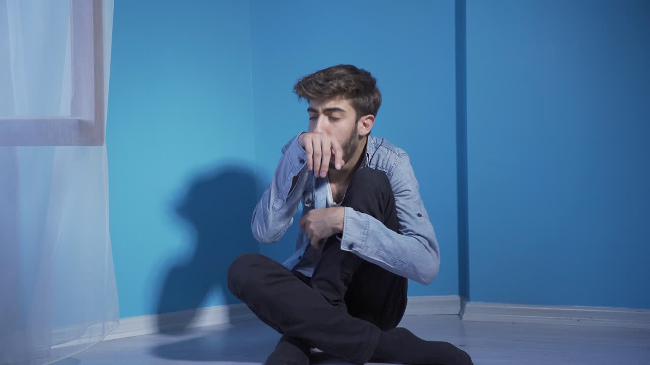 벽에 기대어 기침하는 병든 남자. 절망적.