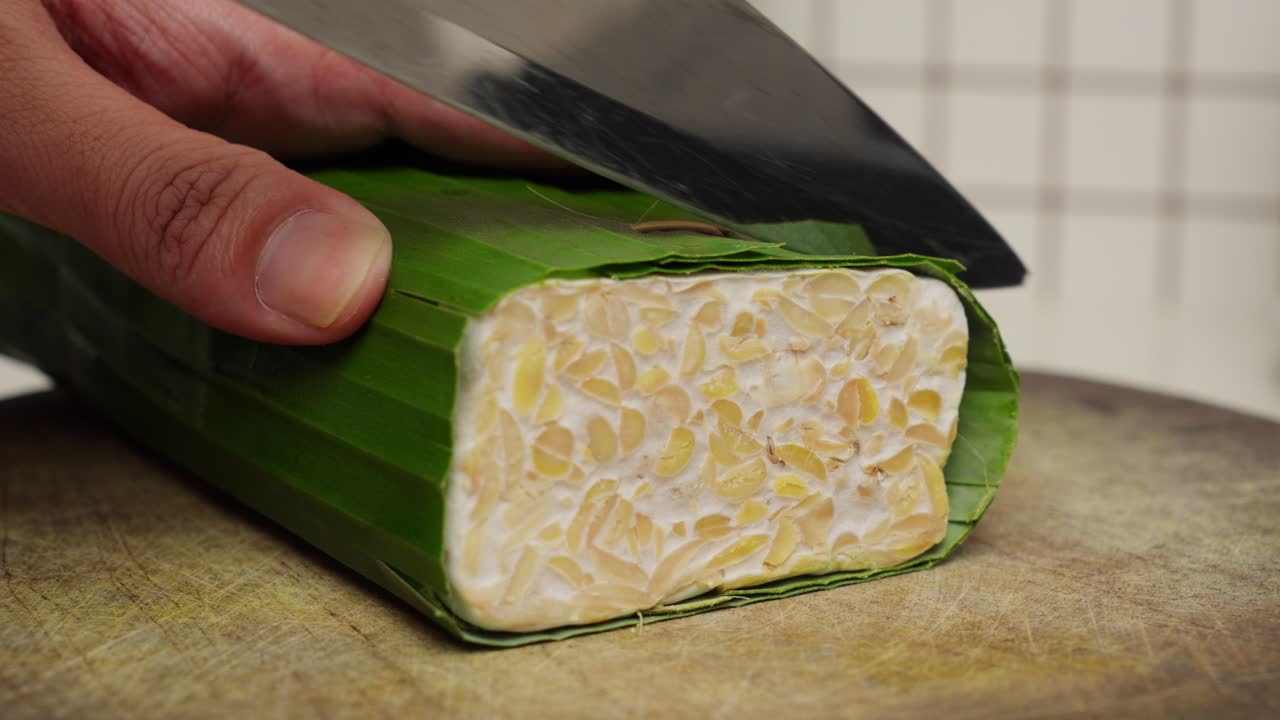 primer plano de tempeh, un plato tradicional indonesio de frijol de soja fermentado que se está cortando
