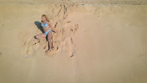 a young woman in a vibrant blue bikini relaxes on a tropical paradise island beach, surrounded by sand under the sunny sky