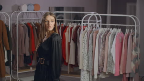 una hermosa chica con un vestido negro se mira en el espejo en la tienda. probando un vestido de noche.