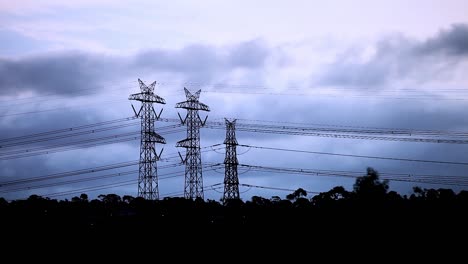 cold evening landscape with dark ominous clouds rolling through the frame past electricity pylons