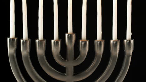 tilt shot of jewish menorah candelabrum with lit candles against black background