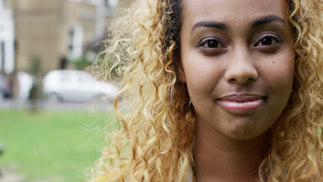 Close-up-portrait-beautiful-young-mixed-race-woman-smiling-at-camera-urban-scene