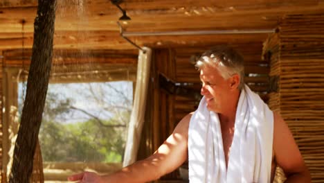 Man-washing-hands-from-shower-in-cottage-during-safari-vacation-4k