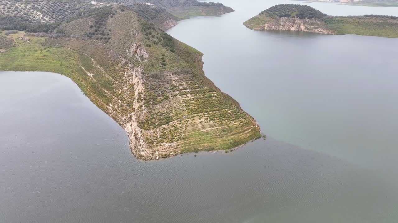 Aerial to strange triangular shape lake headland and water strata levels Spain