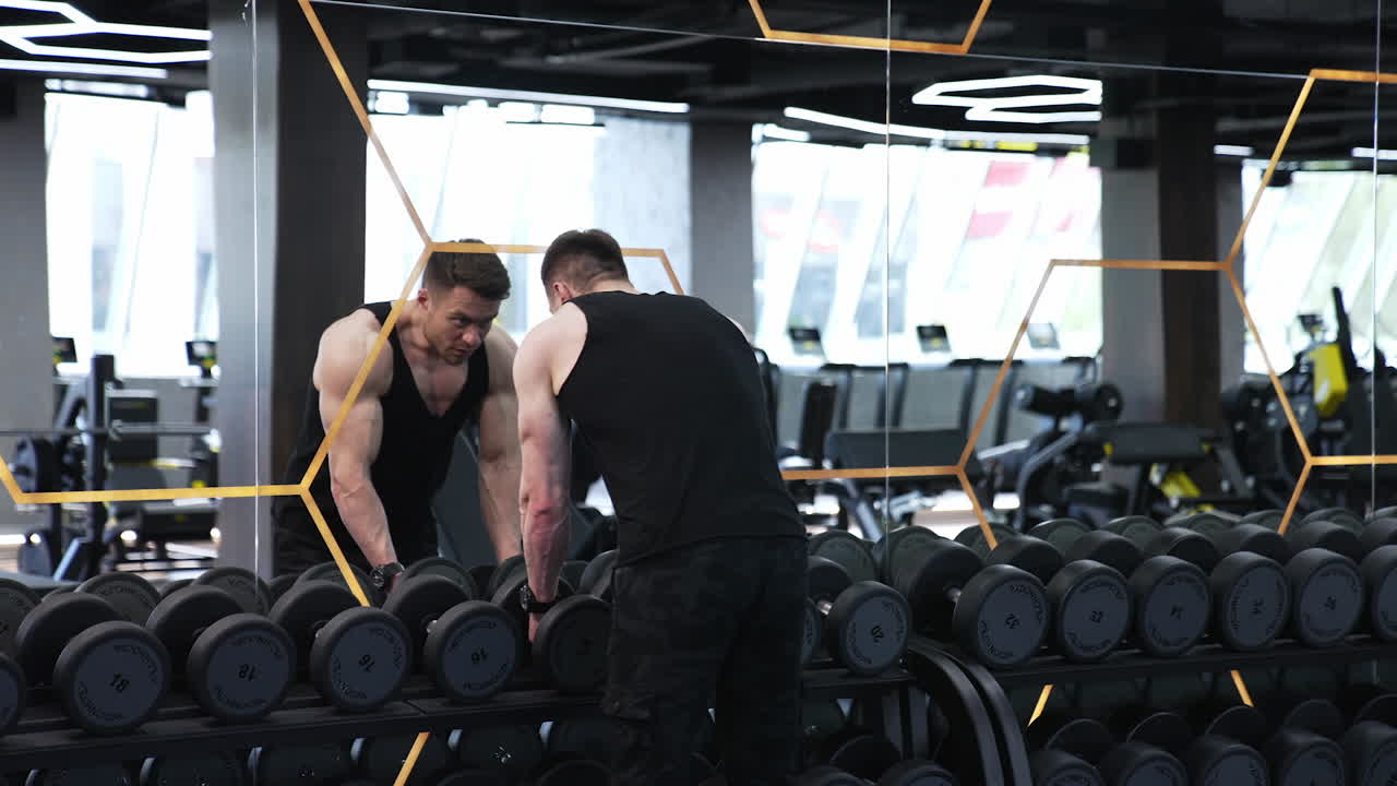 Muscular man doing exercises with dumbbells. Man doing lift ups, holding heavy dumbbells in hands, workout for arm muscles