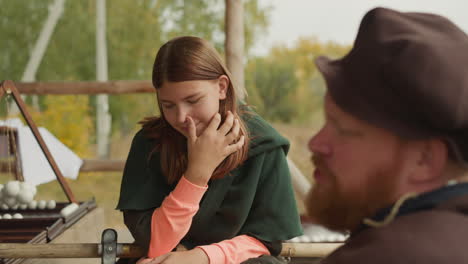 man and girl in medieval clothes talk sitting in yard