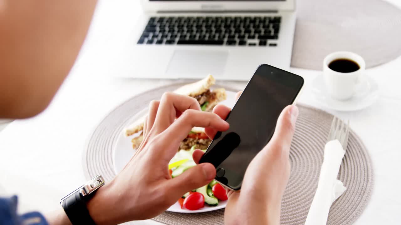 video de un hombre usando un teléfono inteligente con el almuerzo
