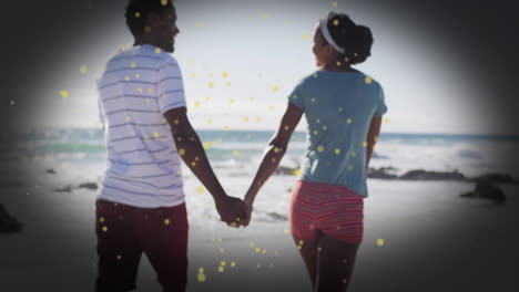 couple holding hands walking on beach with golden sparkles animation overlay