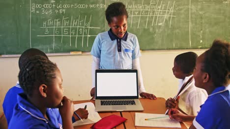 young schoolboy with laptop at the front of class 4k