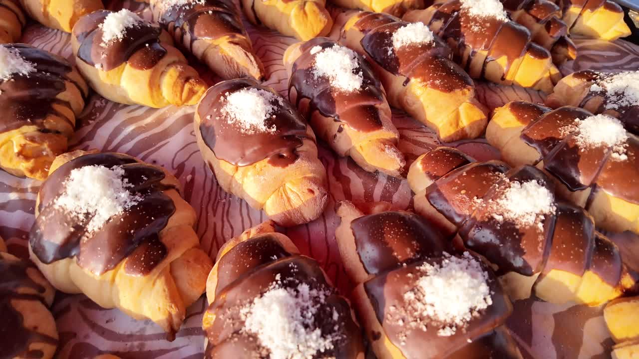 Primo piano di croissant freschi con glassa al cioccolato e zucchero a velo