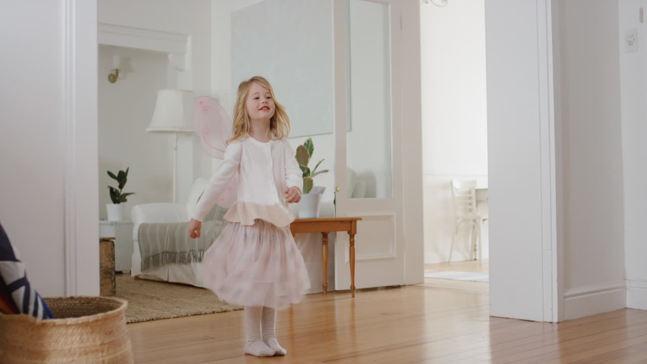 niña feliz bailando juguetón fingiendo ser bailarina divertido niño divirtiéndose jugando a vestirse con alas de hadas traje de ballet en casa 4k