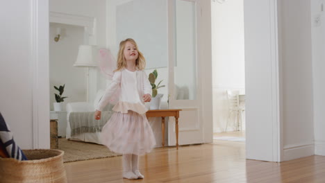 happy little girl dancing playfully pretending to be ballerina funny child having fun playing dress up wearing fairy wings ballet costume at home 4k