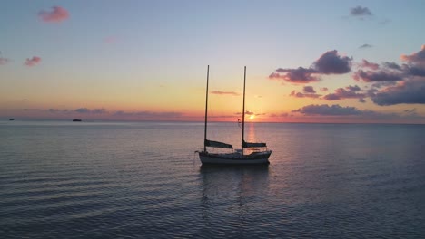 A-Man-Is-Seen-In-A-Canoe-Near-A-Sailboat-In-Thailand-At-Sunset