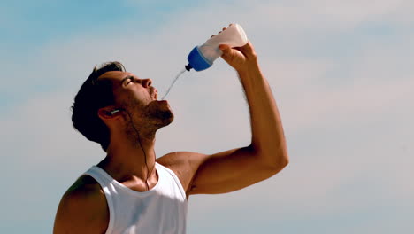 Hombre-Atlético-Rehidratándose-Con-Agua-En-La-Playa