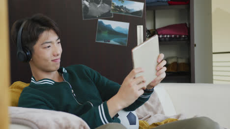 asian boy using digital tablet sitting on the couch at home