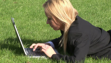 Woman-lying-on-grass-using-laptop-computer