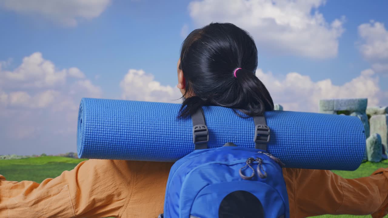 Close Up Back View Of A Female Hiker With Mountaineering Backpack Spreading Arms And Looking The View Around While Traveling In Stonehenge