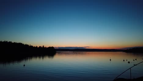 sunset timelapse over calm waters of stockholm archipelago with silhouettes of trees