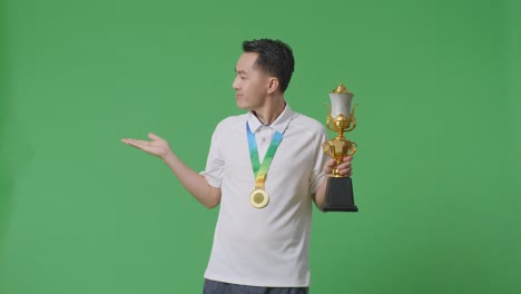 hombre sosteniendo el trofeo y la medalla en la pantalla verde