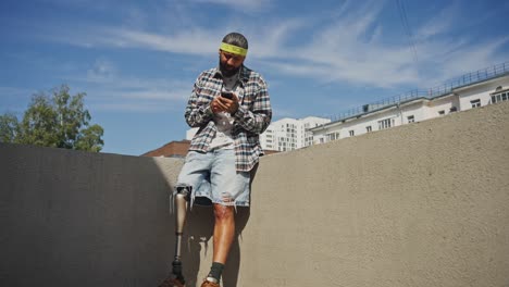 man with prosthetic leg using phone outdoors