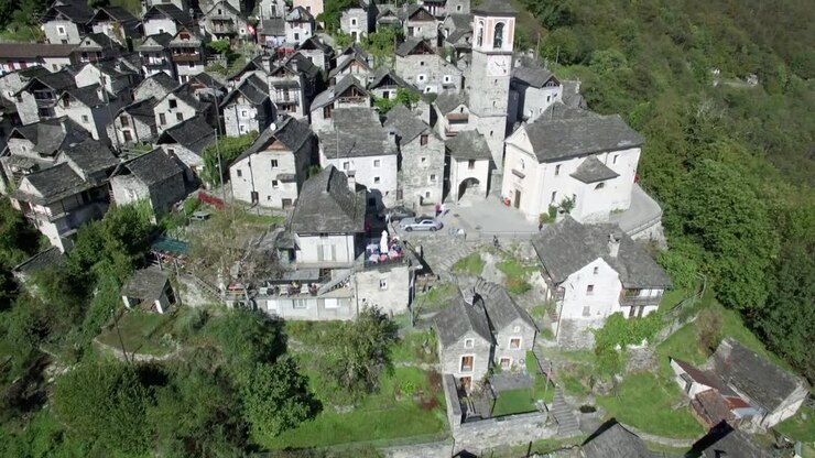 Ripresa aerea rivelatrice del borgo medievale di Corippo tra le montagne, piccolo villaggio montano di Corippo in Ticino, Valle Verzasca, Svizzera