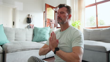 senior man meditating at home, finding peace and relaxation in living room