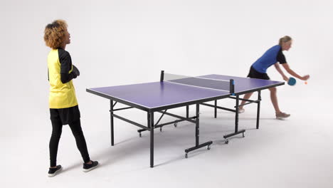 multiracial female table tennis players, serving and passing the ball on white background