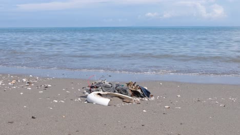 fast fashion clothing trash and plastic trash washed ashore onto beach from beach on tropical island
