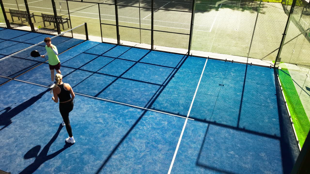 Luftaufnahme von zwei Personen, die Padel-Tennis auf einem blauen Platz spielen