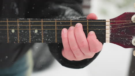 close-up of hand strumming guitar on snow-dusted strings, blending music and winter's beauty, showcasing artistic harmony with frosty details on guitar neck and serene white background