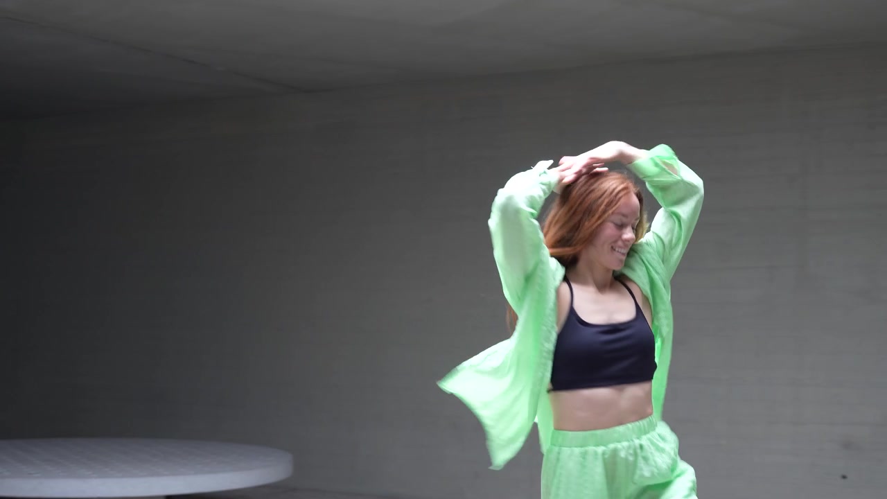 La donna è vestita con un abito verde vivace e si muove con energia sulla pista da ballo