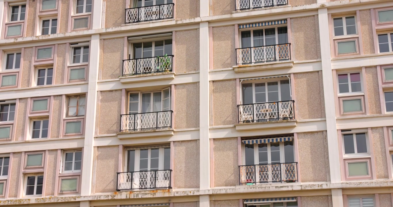 Perret-stil betonlejlighedsblokfacade med smedejernsbalkoner.