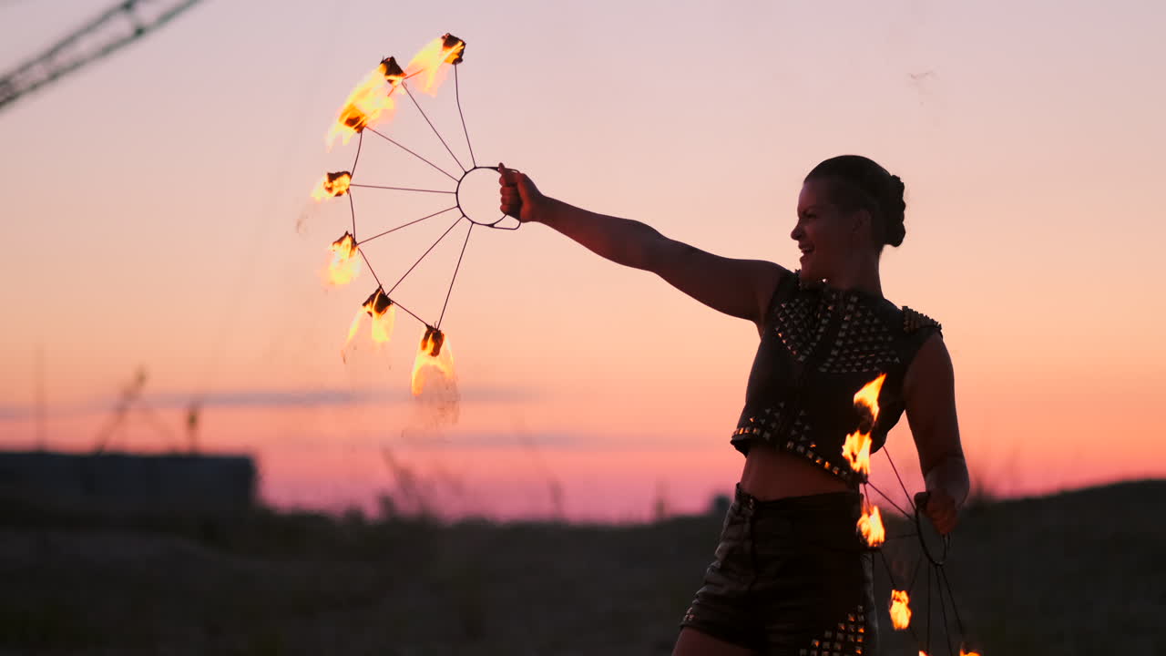 bailarines de fuego contra el atardecer. una joven posa con su aro de fuego contra la puesta de sol durante su actuación de baile