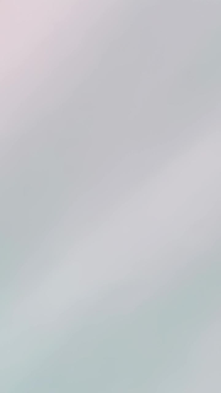 Vertical video: Showing blurred pale wall close-up, shifting tint and brightness without objects