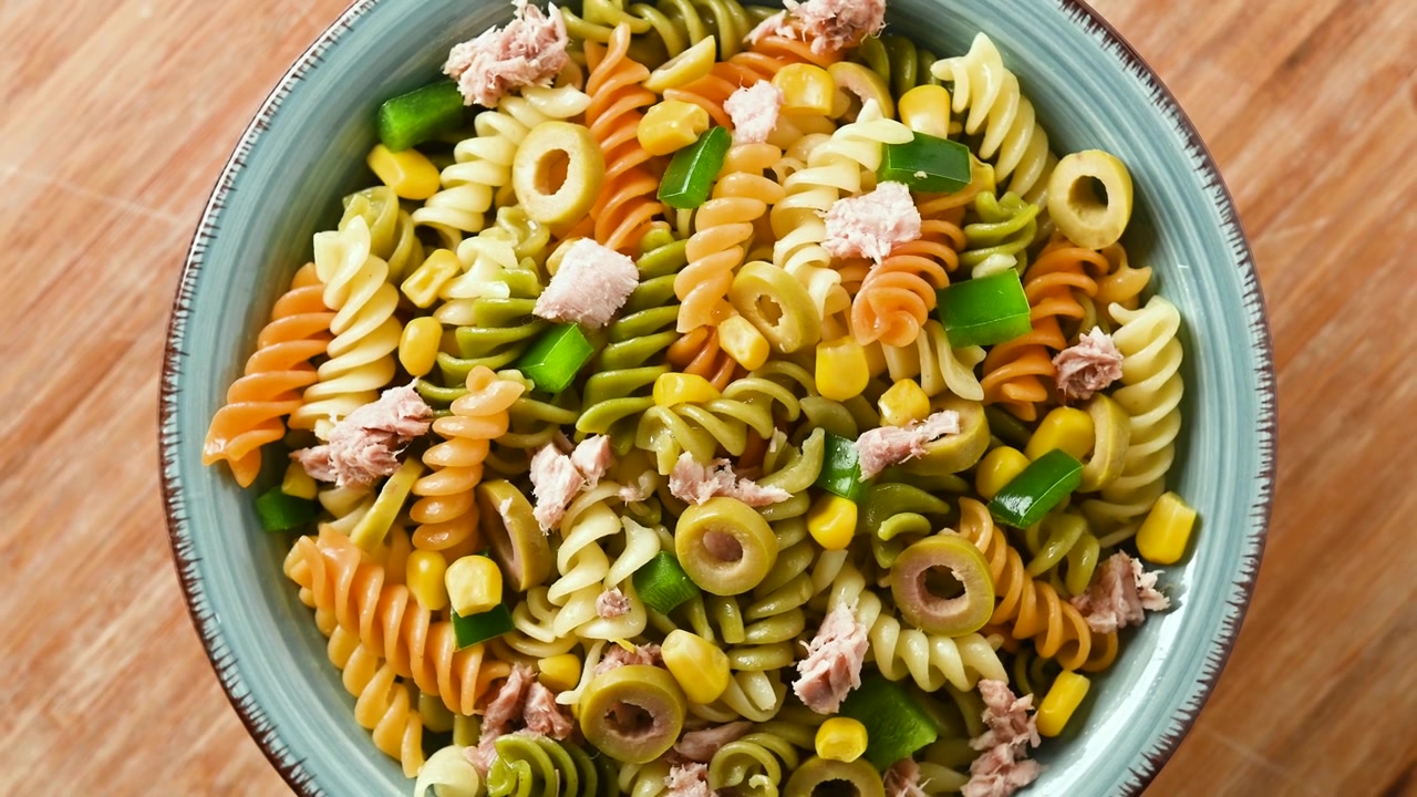 Insalata di pasta con tonno, mais e olive in una ciotola.