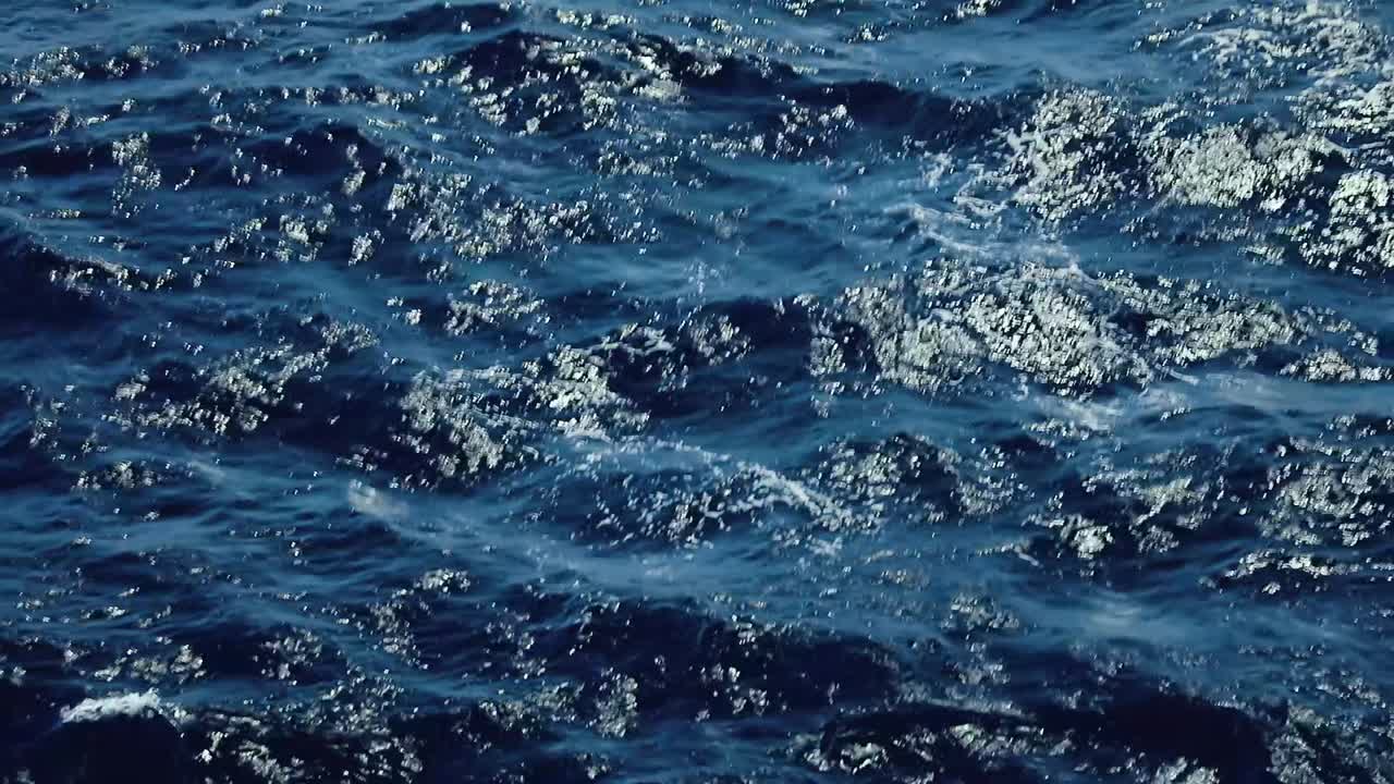 Ondas azuis escuras do oceano movendo-se pela superfície do Mar do Caribe, com a luz do sol cintilando na água do Atlântico durante uma viagem de cruzeiro.