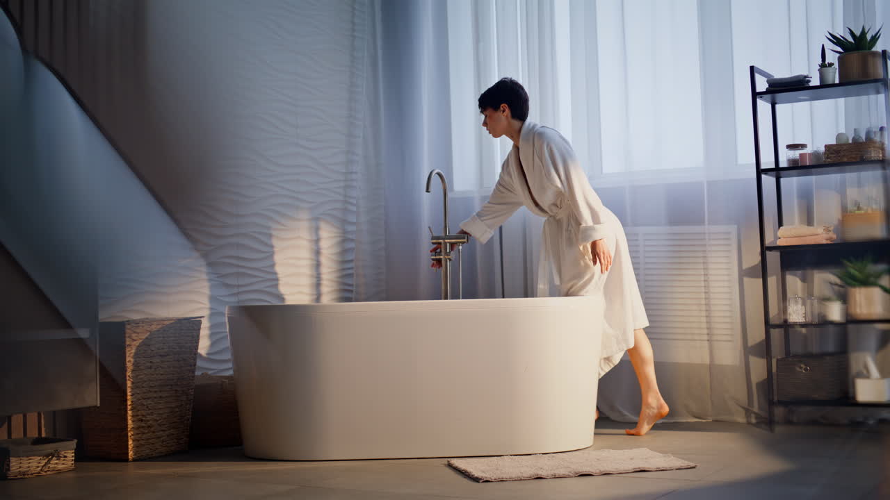 Donna a piedi nudi che entra in bagno in una dolce mattina. Donna che apre il rubinetto dell'acqua calda.