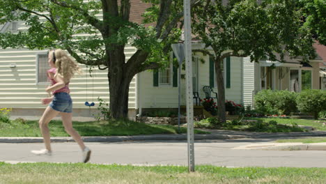 enthusiastic young girl dancing down the street to music in her headphones