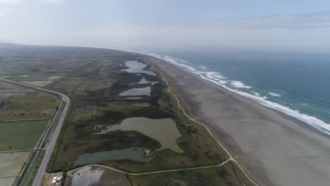 an aerial shot of coastal wetlands blending into the ocean. a serene mix of water, sand, and greenery. ideal for travel, conservation, or editorial use. mejia, arequipa, peru.