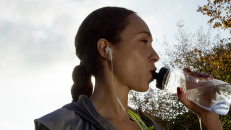 Runner woman drinking water bottle sun flare solar energy