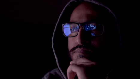 an underground cryptocurrency trader focused on his computer screen in the dark, his glasses reflecting an animation of the increased market performance graph of the nft he is following