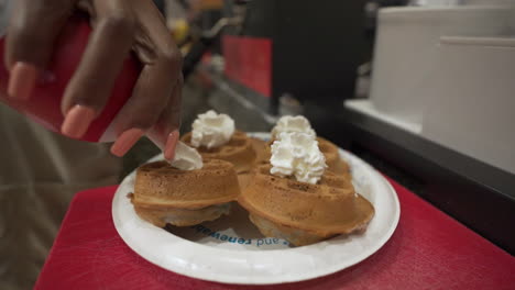 spraying whip cream on belgian waffles