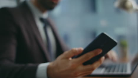 busy businessman taking cellphone looking screen sitting at office desk close up