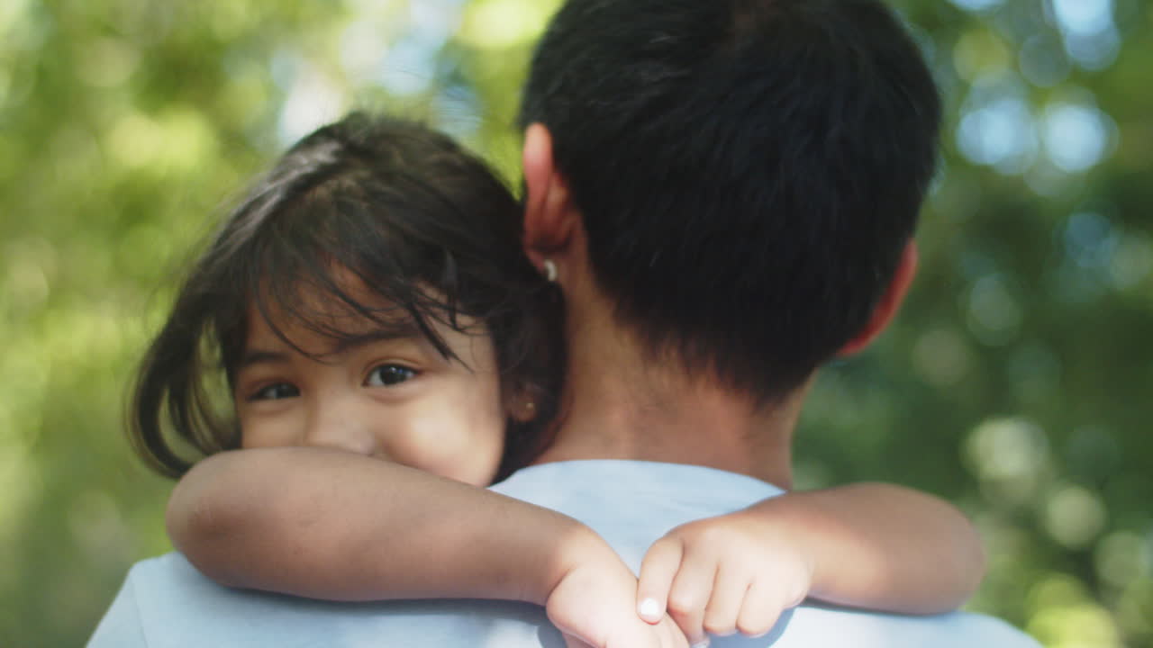 primer plano de niña asiática en el hombro de su padre al aire libre