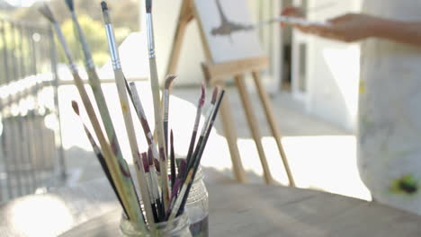 Senior-biracial-woman-painting-at-balcony-at-home,-slow-motion