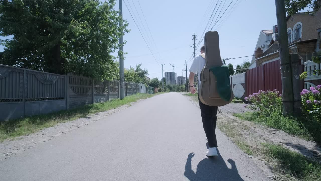 숲 근처의 거리에서 기타를 들고 는 젊은 남자